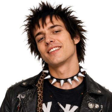Jeune homme souriant avec une coupe de cheveux hérissée portant un collier punk noir doté de grandes pointes argentées métalliques | jourdefete.com Jeune homme souriant avec une coupe de cheveux hérissée portant un collier punk noir doté de grandes pointes argentées métalliques | jourdefete.com