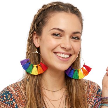 Jeune femme souriante portant des boucles d'oreilles créoles ornées de pompons multicolores arc-en-ciel | jourdefete.com Jeune femme souriante portant des boucles d'oreilles créoles ornées de pompons multicolores arc-en-ciel | jourdefete.com